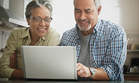 Older couple smiling and looking at computer