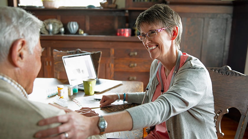 Smiling home caregiver touching the shoulder of a senior man