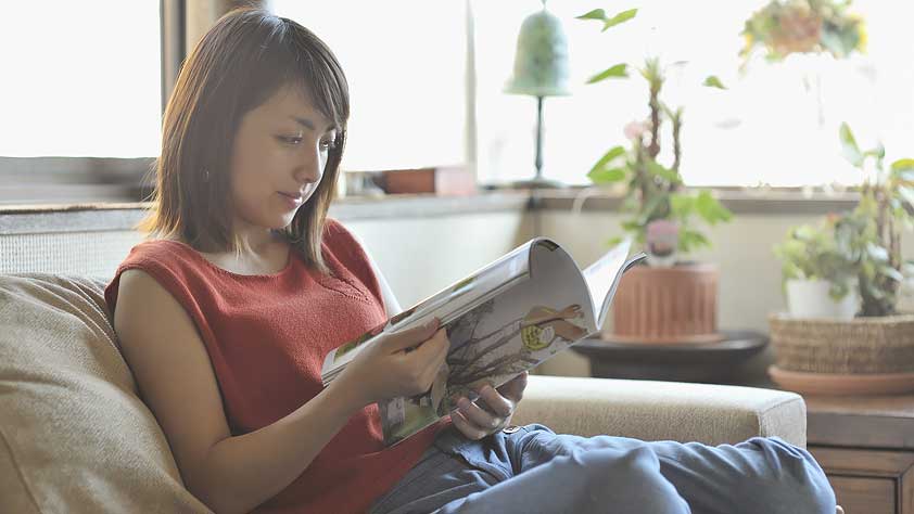 Young Woman Reading a Magazine to Help Keep New Year’s Resolutions