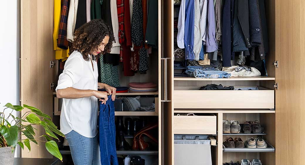 Woman Putting Clothes Into Her Well-Organized Closet