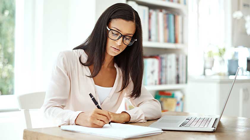 Should I Refinance My Student Loans - Young Woman Using a Laptop and Writing Notes