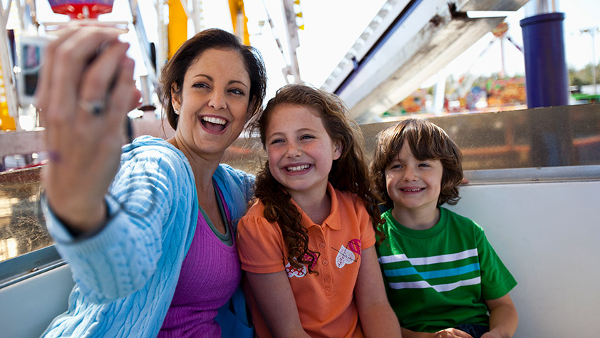 Mother taking a selfie with her daughter and son while riding on a Ferris wheel