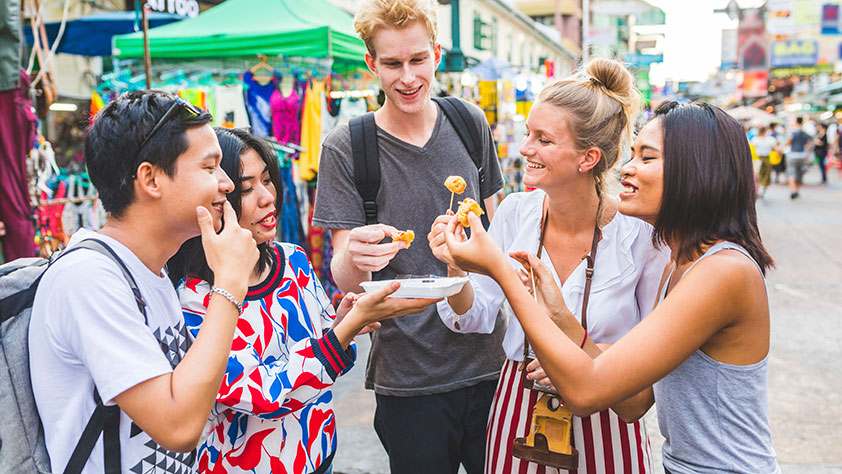 Group of friends tasting local food at a street festival