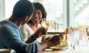 Smiling African-American couple drinking wine and enjoying a meal in a café