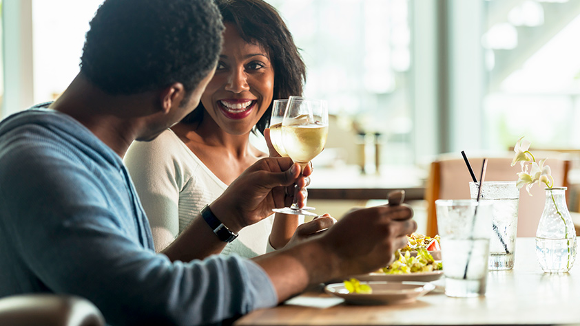 Smiling African-American couple drinking wine and enjoying a meal in a café