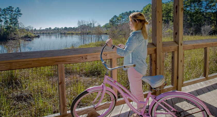 Woman on a pink bike looking out over wetlands in Tammany Trace, Covington to Slidell, Louisiana