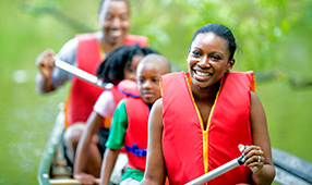 Close-up of a family of four in red life jackets canoeing on a lake