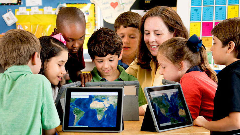Teacher and students using digital tablets to look at maps