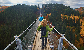 Hikers Walking Across a Forest Bridge in Fall