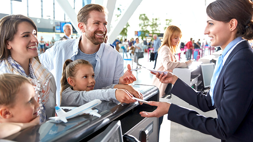 Customer service representative helping a family check in at the airport ticket counter