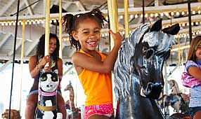 Young Girl at Amusement Park Riding a Carousel Horse