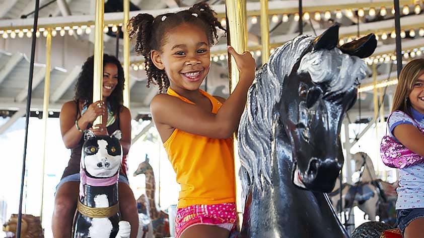 Young Girl at Amusement Park Riding a Carousel Horse