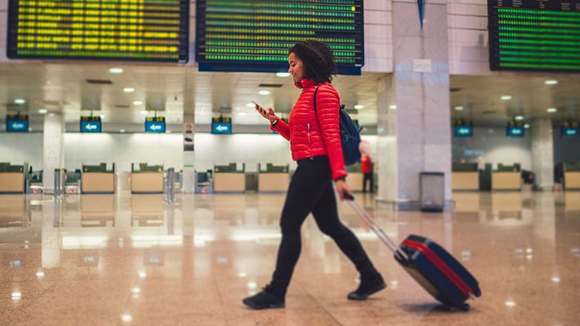 Woman walking through an airport with her wheeled suitcase