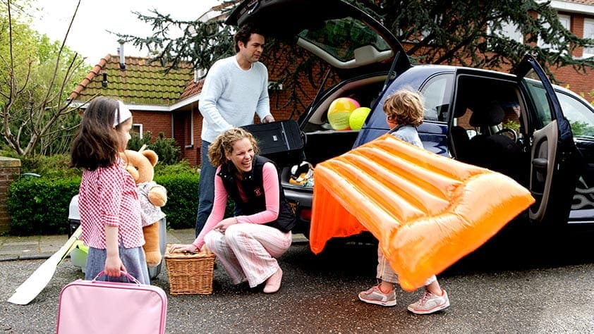 Family of four packing their car for a summer trip