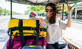 Woman on vacation riding in a rickshaw with her luggage