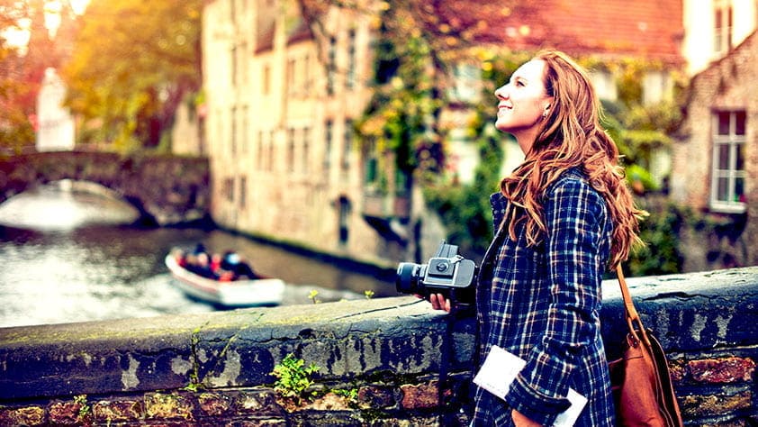 Young woman with a camera enjoying travel to Bruges, Belgium