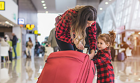Mother and Daughter with a Red Suitcase at the Airport