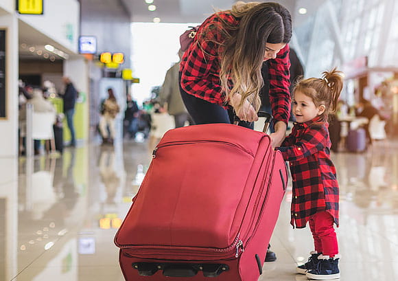 Mother and Daughter with a Red Suitcase at the Airport