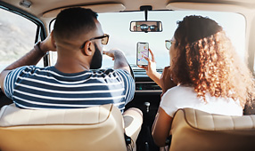 Young Couple Using GPS on Their Mobile Phone During a Road Trip