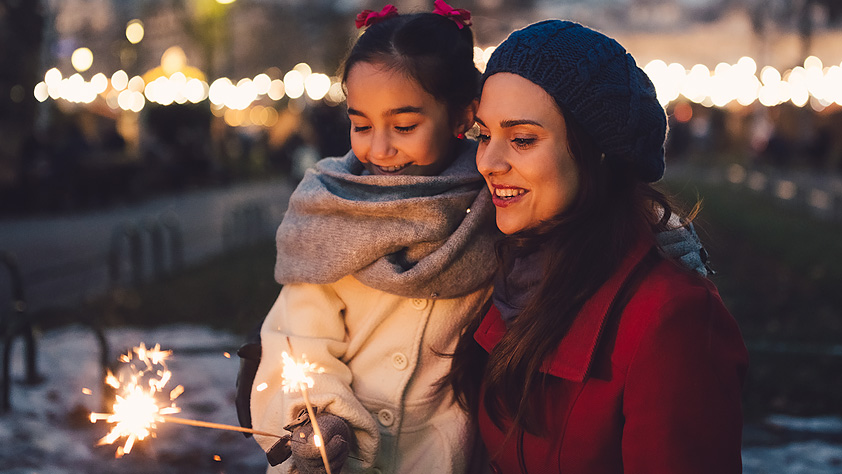 Mother and daughter holding sparklers at a winter event