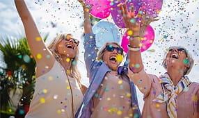 Excited Women Celebrating Outdoors with Colorful Confetti and Balloons