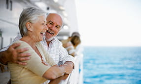 Happy older couple looking off the side of a cruise ship