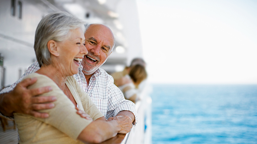 Happy older couple looking off the side of a cruise ship