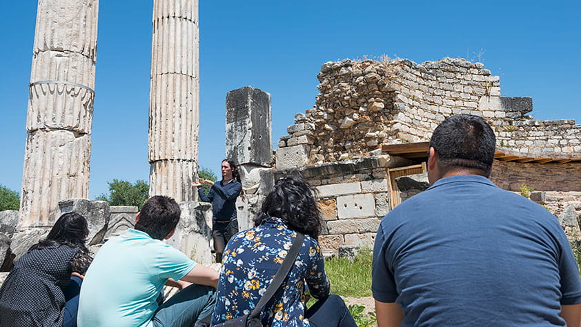 Guide explaining to tourists the ruins of stone columns and structures