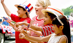 Children dressed in red, white and blue cheering at fourth of July celebration