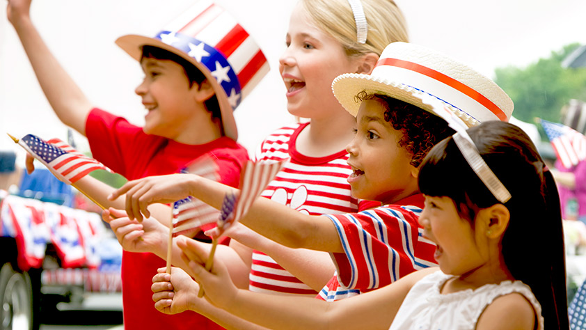 Children dressed in red, white and blue cheering at fourth of July celebration