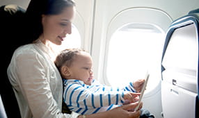Mother and toddler son sitting in an airplane using a digital tablet