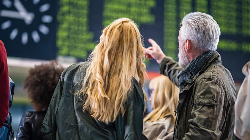 Couple Looking at Train Schedule at Train Station