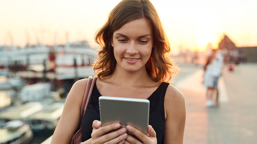 Woman Staring at Tablet on Dock at Sunset