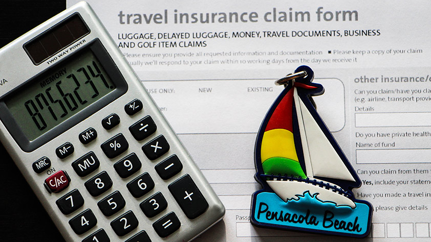 Close-up of a calculator, a key ring in the shape of a colorful sailboat and a travel insurance claim form
