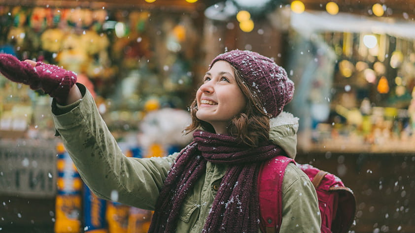 Smiley woman enjoying snow falling
