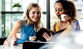 Friends meeting in cafe, talking and sharing news while using a digital tablet