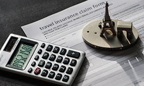 Close-up to travel insurance orm, calculator and eiffel tower miniature