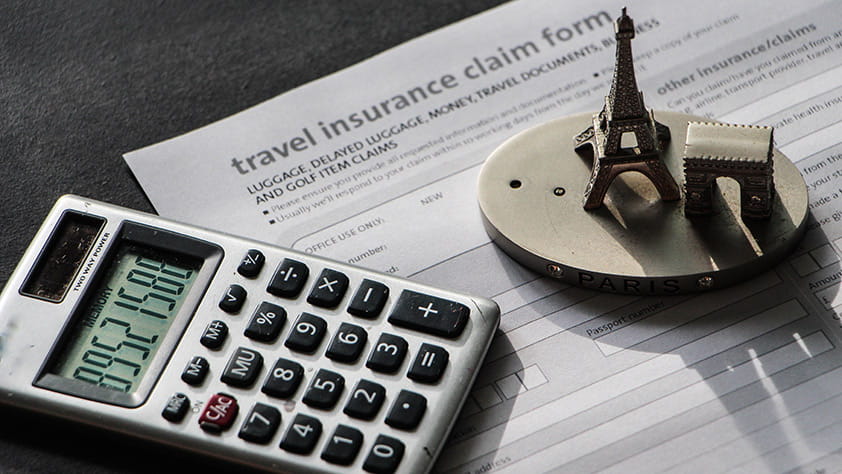 Close-up to travel insurance orm, calculator and eiffel tower miniature