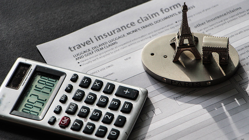 Close-up to travel insurance orm, calculator and eiffel tower miniature
