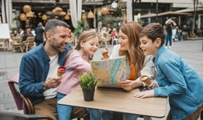 Smiling family of four, looking over a map and planning their vacation with the NEA Travel Program