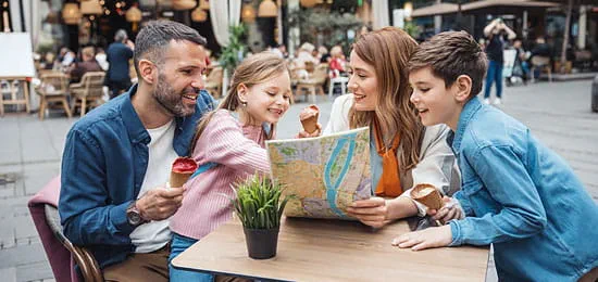 Smiling Family of Four, Looking Over a Map and Planning Their Vacation with the NEA Travel Program