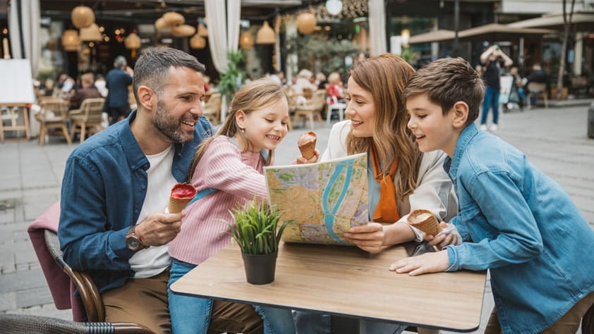 Smiling family of four, looking over a map and planning their vacation with the NEA Travel Program