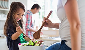 Mother and young daughter making a healthy salad together