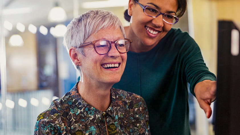 An older woman and a younger woman working at a computer together