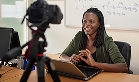 Young Female Teacher Sitting in Front of a Camera Teaching an Online Class