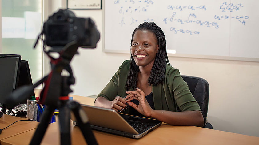 Young Female Teacher Sitting in Front of a Camera Teaching an Online Class