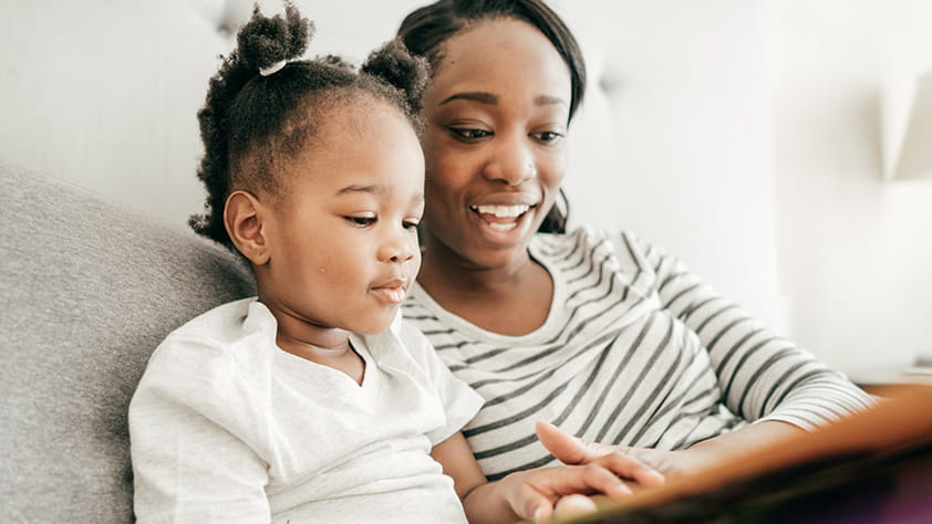 Mom Reading to Daughter on Couch