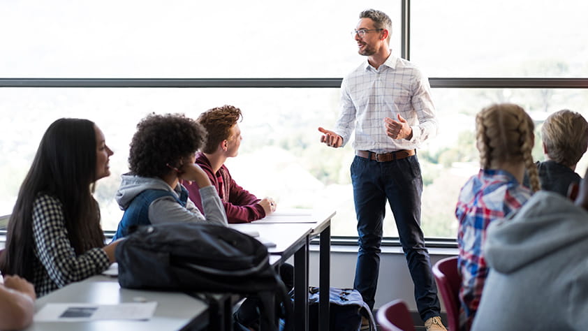 Male teacher explaining a lesson to a group of high school students