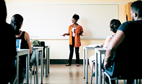Female teacher in front of a classroom filled with parents