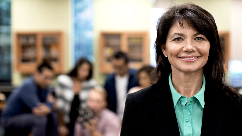 Portrait of a high school teacher with her students and classroom out of focus in the background